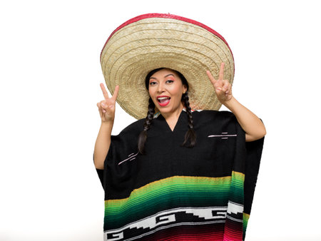 Smiling Mexican woman wears colorful poncho and big hat, isolated on white background.の写真素材