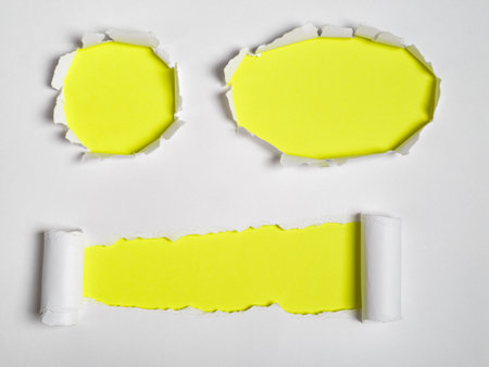 Set of three torn holes in white paper revealing a yellow background. Space for text.の写真素材