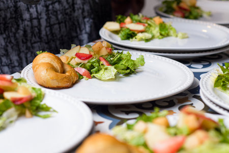 A table set with several plates of fresh fruit salad and lettuce, each accompanied by a small croissant. A catering event in progress.の写真素材