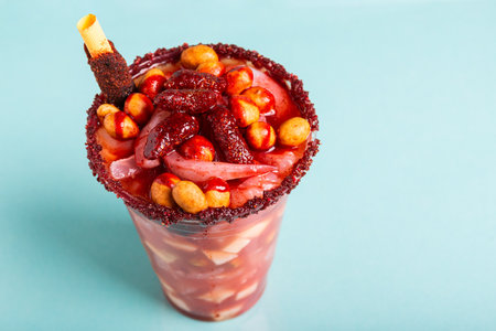 Crazy little glass, a mixture of sweet, salty and spicy ingredients isolated on blue background....