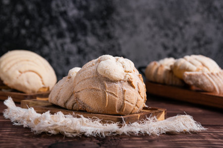 Concha breads, dusted with sugar, rest on a rustic wooden board