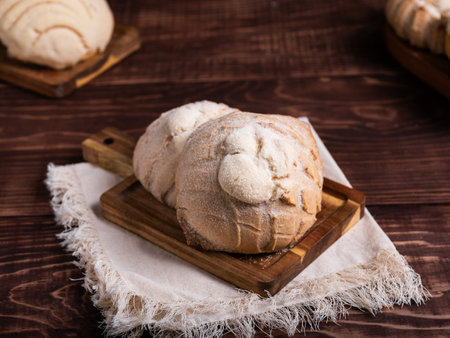 Concha breads, dusted with sugar, rest on a rustic wooden boardの写真素材