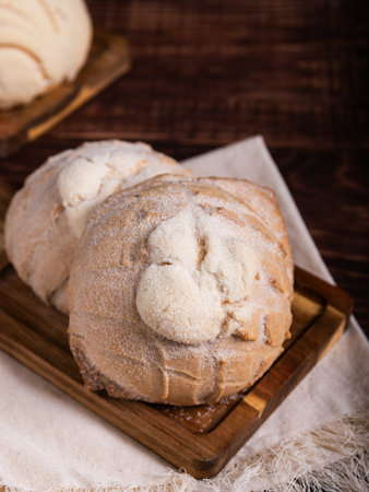 Concha breads, dusted with sugar, rest on a rustic wooden board