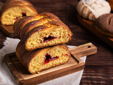Typical mexican sweet bread on wooden table. Braided bread filled with jam.