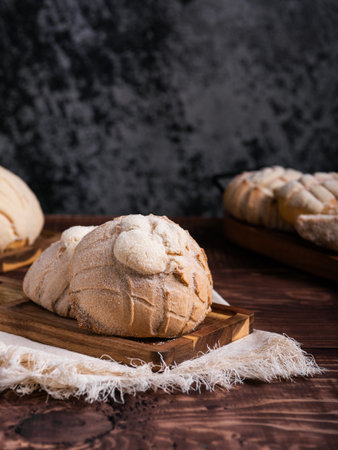 Concha breads, dusted with sugar, rest on a rustic wooden board