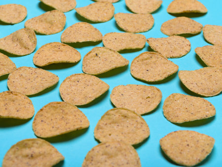 Numerous round nachos carefully arranged on a light blue-green background.