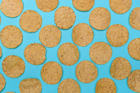 Numerous round nachos carefully arranged on a light blue-green background.の写真素材