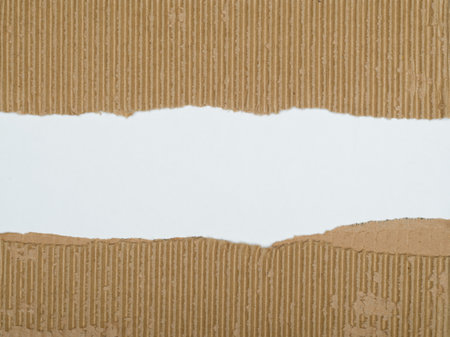 A piece of corrugated cardboard with its center torn away, revealing a plain white backgroundの写真素材