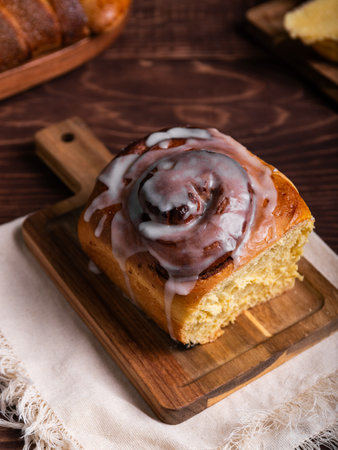 Sweet cinnamon roll on a wooden board on a rustic table, accompanied by an assortment of pastries.の写真素材