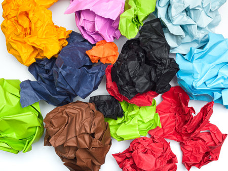 A vibrant collection of crumpled papers in various colors is scattered across a white background.の写真素材