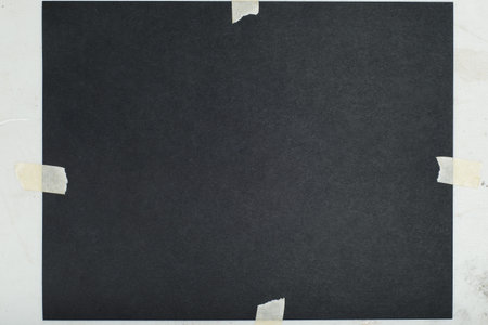 A dark square piece of paper, possibly cardstock, is taped to a lighter background