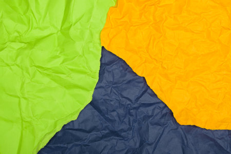 Crumpled paper in green, orange, and navy blue.の写真素材
