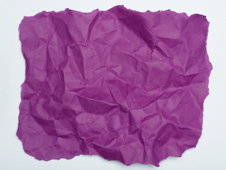 A crumpled piece of deep purple paper, its edges torn and uneven, against a plain white background.の写真素材