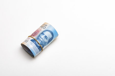 Roll of Mexican pesos against a stark white background.の写真素材