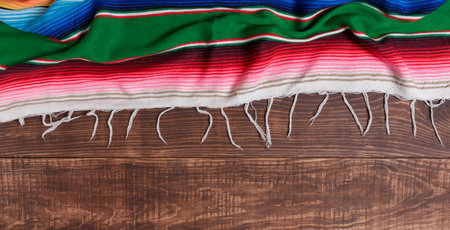 Colorful serape on wooden table. Typical colorful fabric from Mexico. Texture, background.の写真素材