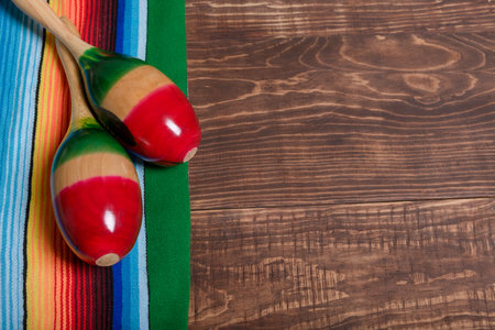 Colorful serape and maracas on wooden table. Typical colorful fabric from Mexico. Texture,...