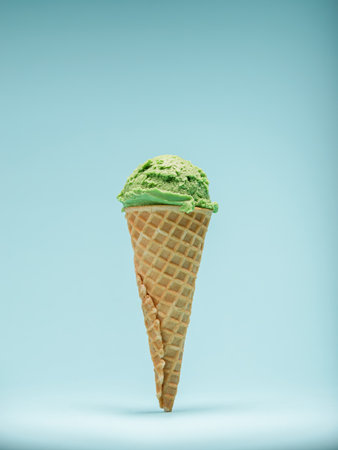 A scoop of vibrant green mint ice cream on top of a crispy waffle cone, against a pale blue...