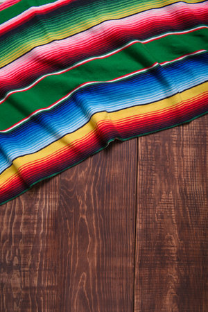 Colorful serape on wooden table. Typical colorful fabric from Mexico. Texture, background.の写真素材