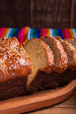 Salvadoran yolk bread with sesame seeds, on a wooden tray