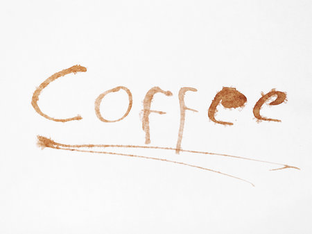The word Coffee artfully written in coffee stains on white paper.の写真素材