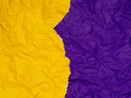 A torn and crumpled piece of yellow paper on a background of crumpled purple paper.の写真素材