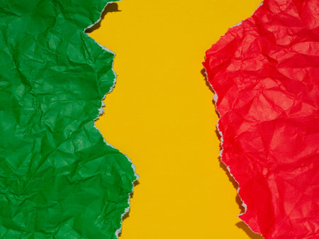 Pieces of red and green paper torn and crumpled on a yellow background.の写真素材