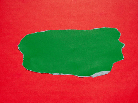 Piece of torn green paper on a red background.の写真素材