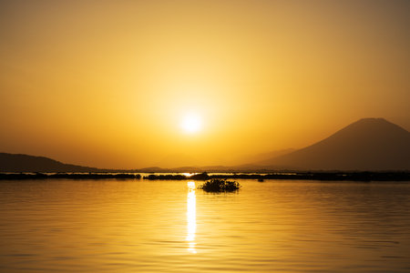 Serene Silhouette Golden Hour Sunset Over Calm Lake Landscapeの写真素材