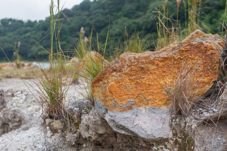 Peaceful outdoor landscape with orange rock in the foreground and mountain covered in green grassの写真素材