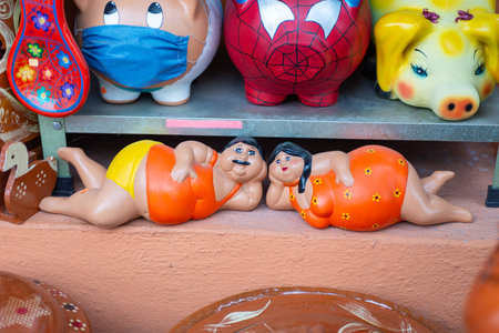 Vivid Ceramic Curvy Couple Figurine with Colorful Piggy Banks on Displayの写真素材