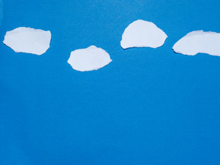 Simple cloud of torn paper against a blue sky background.の写真素材