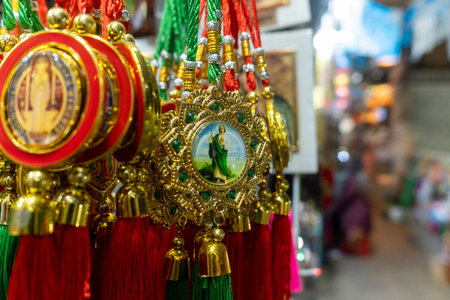 Close-up of ornate hanging Saint medals souvenirs with red and green tassels. Religious trinkets,の写真素材