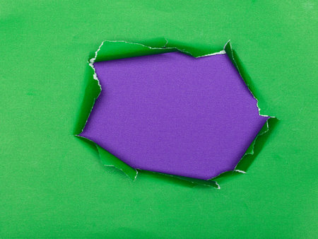 Torn green paper revealing a shiny purple surface underneath.の写真素材