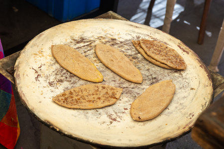 Close-up shot of tlacoyos, a traditional Mexican dish, being cooked on a comal.