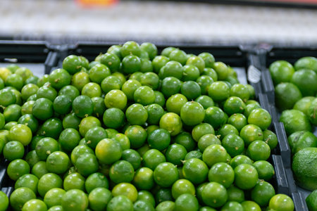 Fresh green lemons in a black box at the market.の写真素材