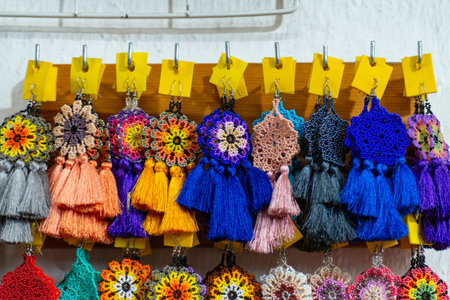 Handmade beaded tassel earrings displayed on a wooden rackの写真素材