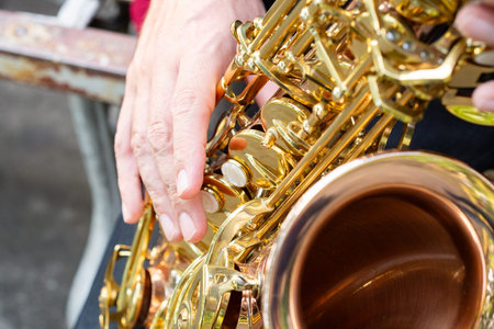 An elegant musician playing a golden saxophone outdoors. Close up.の写真素材