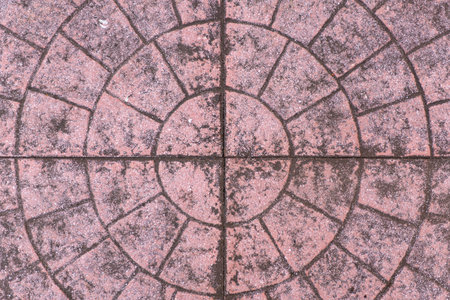 Circular design of aged pink concrete pavement with a rough texture.