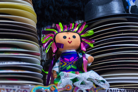 Colorful authentic Mexican doll displayed among stacked hats. Souvenir. Lele doll.の写真素材