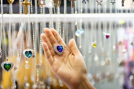 A close-up shot capturing a hand gently holding a heart shaped pendant necklace.