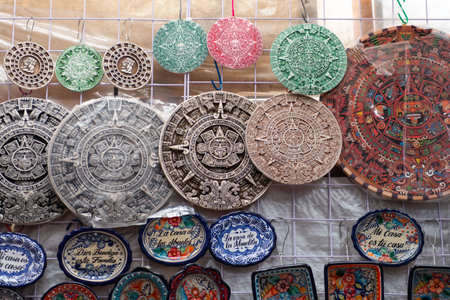 A diverse collection of handmade souvenirs featuring Mayan calendar designs and decorative plates...