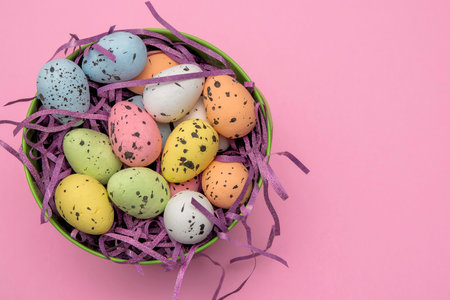 A green easter basket filled with pastel easter eggs and purple sparkly basket filler.の写真素材