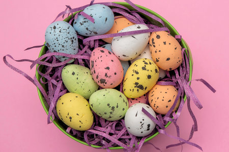 A green easter basket filled with pastel easter eggs and purple sparkly basket filler.の写真素材