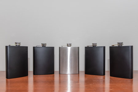 The groom's silver whisky flask along with four black flasks for his groomsmen's gifts.の写真素材