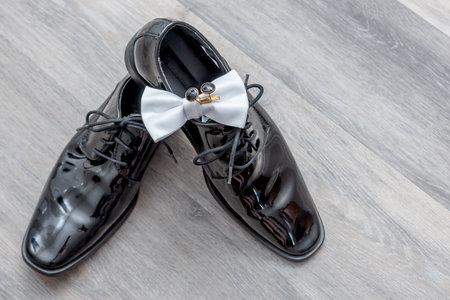 A display of the groom's black wedding shoes, white bowtie and his black and silver cufflinks.の写真素材