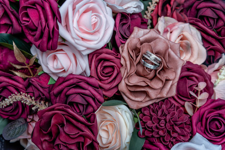 Silver wedding rings inside beautiful shades of pink and rose wedding bouquet.の写真素材