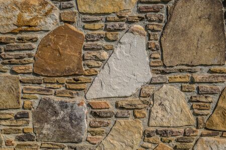 Variety of rocks with different shapes stacked together between mortar for a wall of a building...
