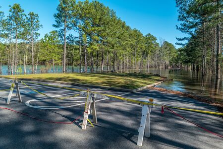Record rain fall at Lake Lanier Georgia closing Little ridge park with barricades and caution tape for no entry to the flooded parking lot on a sunny day in winterの写真素材