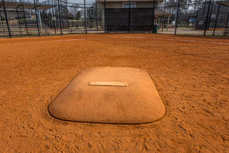 Standing in front of a pitchers mound looking towards home base in a baseball field at a empty park in early springtime closeup viewの写真素材