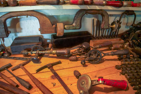 A collection of old woodworking tools laying on a workbench assortment of cranking hand drills and...